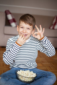 Portrait of boy eating food while sitting at home