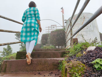 Rear view of woman with umbrella walking on staircase