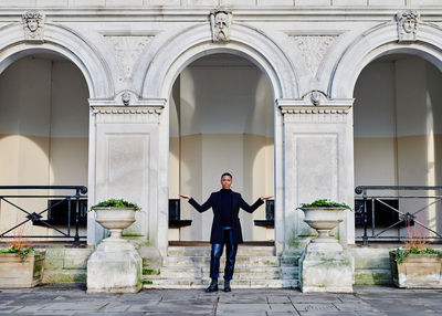 Portrait of young man standing against building