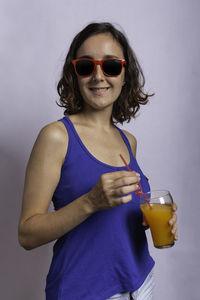 Mid adult woman wearing sunglasses standing against wall
