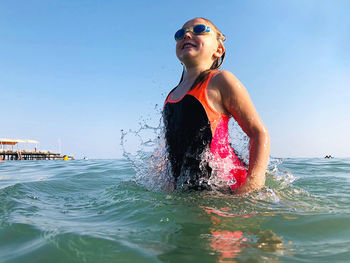 Girl swimming in sea against sky