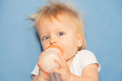 High angle view of cute baby girl with water bottle against blue background