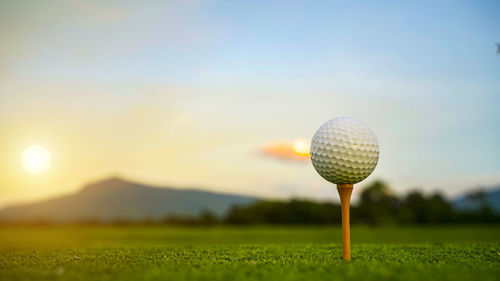 Golf ball on field against sky during sunset