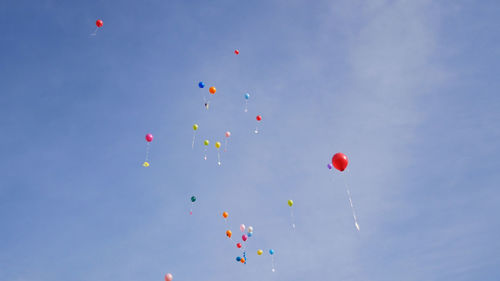 Low angle view of balloons flying against blue sky