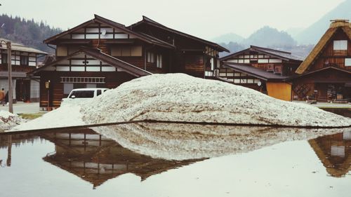 Houses by lake against sky during winter