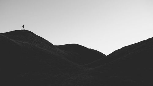 Silhouette man standing on mountain against clear sky