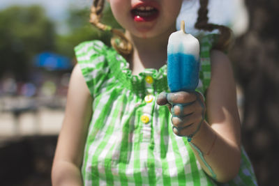 Midsection of girl holding melting flavored ice