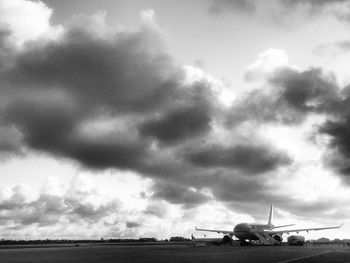 Airplane on airport runway against sky