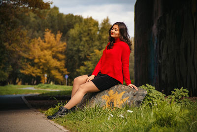 Portrait of young woman sitting on street during autumn