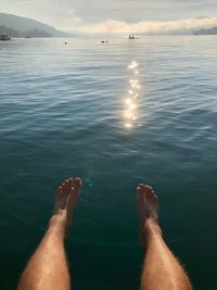 Low section of person in sea against sky