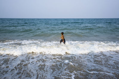 Man walking on beach against clear sky