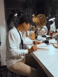 Side view of woman holding food on table in restaurant