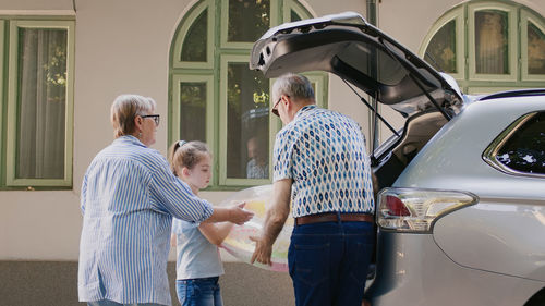 Side view of couple standing against car