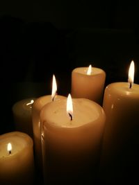 Close-up of burning candles in darkroom