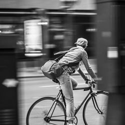 Double exposure of man riding bicycle on road against building