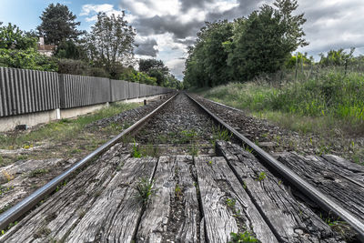 Railroad tracks against cloudy sky