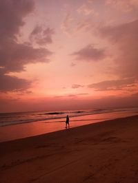 Silhouette people on beach against sky during sunset