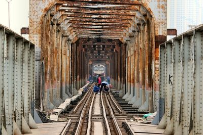 Rear view of man on railroad tracks amidst buildings