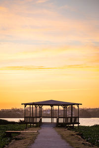 Bridge over sea against orange sky