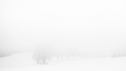 Snow covered land against clear sky during winter