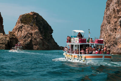 People on boat in sea against sky