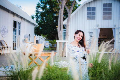 Portrait of smiling young woman standing against plants