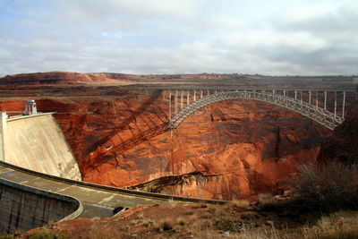 Bridge over road against cloudy sky