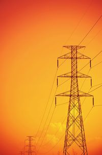 Low angle view of silhouette electricity pylon against romantic sky