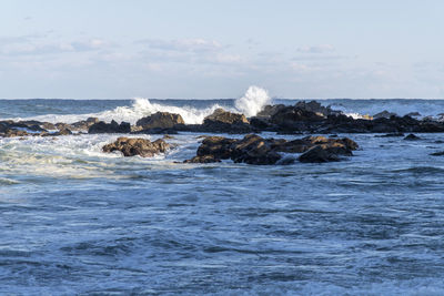 Scenic view of rocks in sea against sky