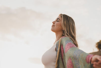 Young woman standing against sky