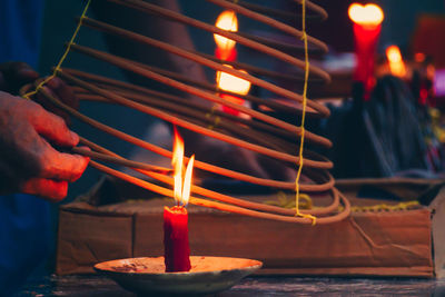 Close-up of people igniting incense with candle on table