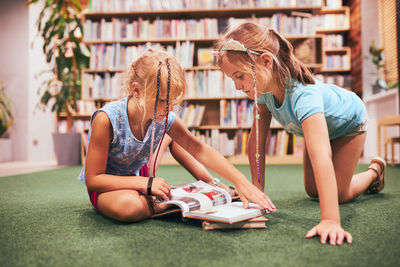 Two schoolgirls reading books in school library. primary school students learning from books