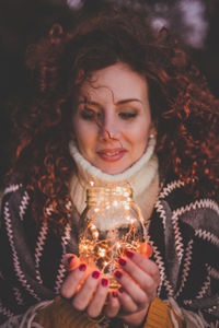 Woman holding illuminated lights in jar