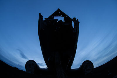 Low angle view of silhouette ship against blue sky