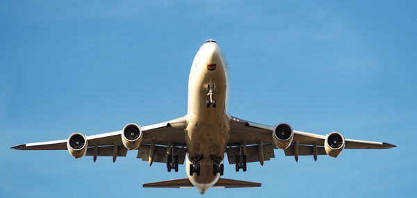 Low angle view of airplane against clear blue sky