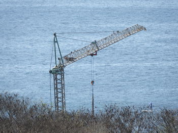 High angle view of cranes by sea against sky