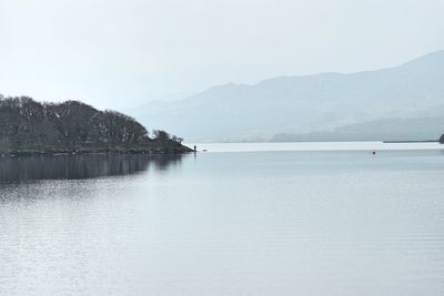 Idyllic shot of sea and mountains against sky