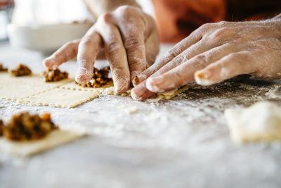 Cropped hand of man preparing food on table in kitchen