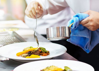 Midsection of man preparing food in plate