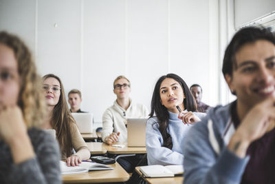 Multi-ethnic male and female students sitting at desk in classroom