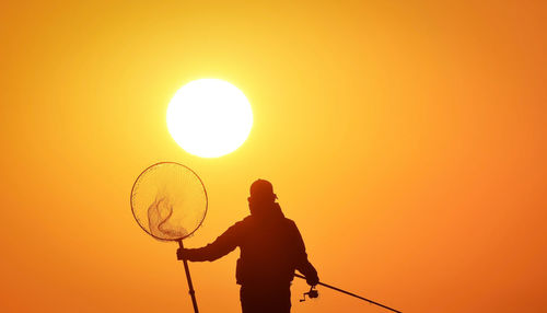 Silhouette man standing against orange sky