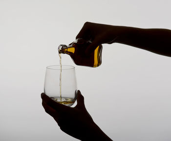 Person hand holding glass of bottle against white background