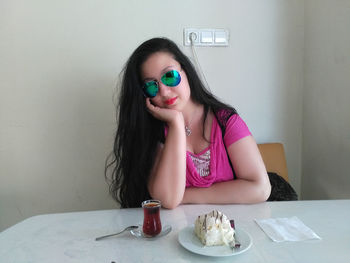 Young woman sitting by dessert and drink at table in cafe