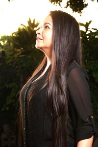 Beautiful young woman standing against tree