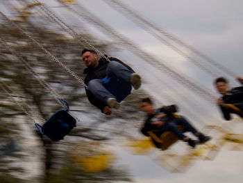 Blurred motion of people enjoying chain swing ride at park