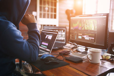 Midsection of film editor working at desk using computer