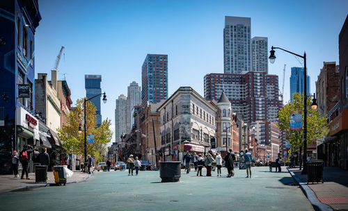 People on city street amidst buildings against sky