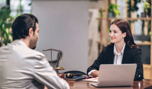 Young woman using mobile phone while sitting on table