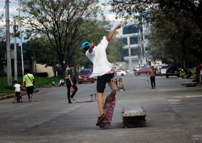 Rear view of man skateboarding on road in city