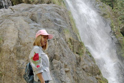 Side view of woman looking at waterfall
